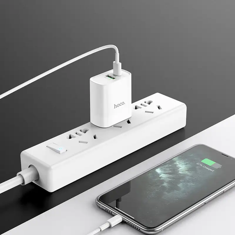 A lifestyle image of the charger plugged into a wall socket with two devices connected