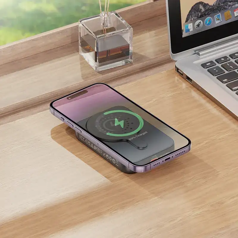 Sleek Hoco J117A 10000mAh magnetic wireless power bank charging an iPhone on a clean desk setup.