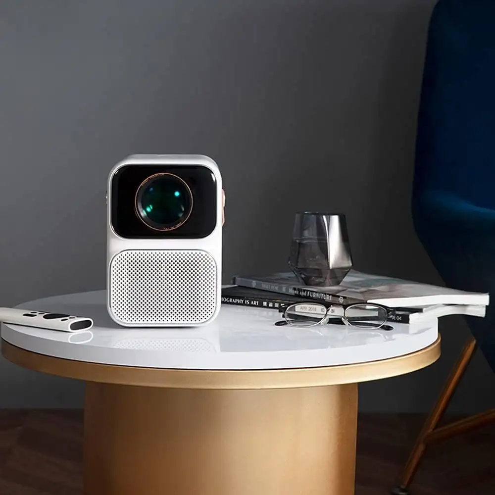 A living-room setup image showing the projector displaying a large screen,