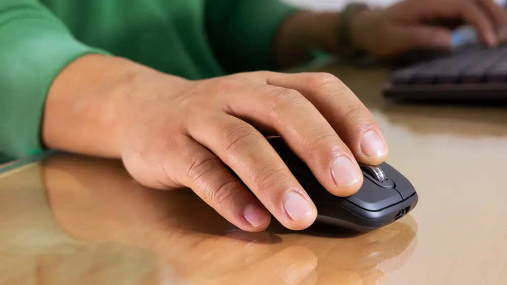 hand using Logitech MX Anywhere 3S wireless mouse on desk showing compact ergonomic design